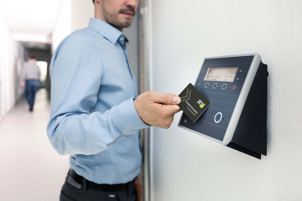 Home Businessman uses RFID card reader for secure office access, enhancing workplace security.
