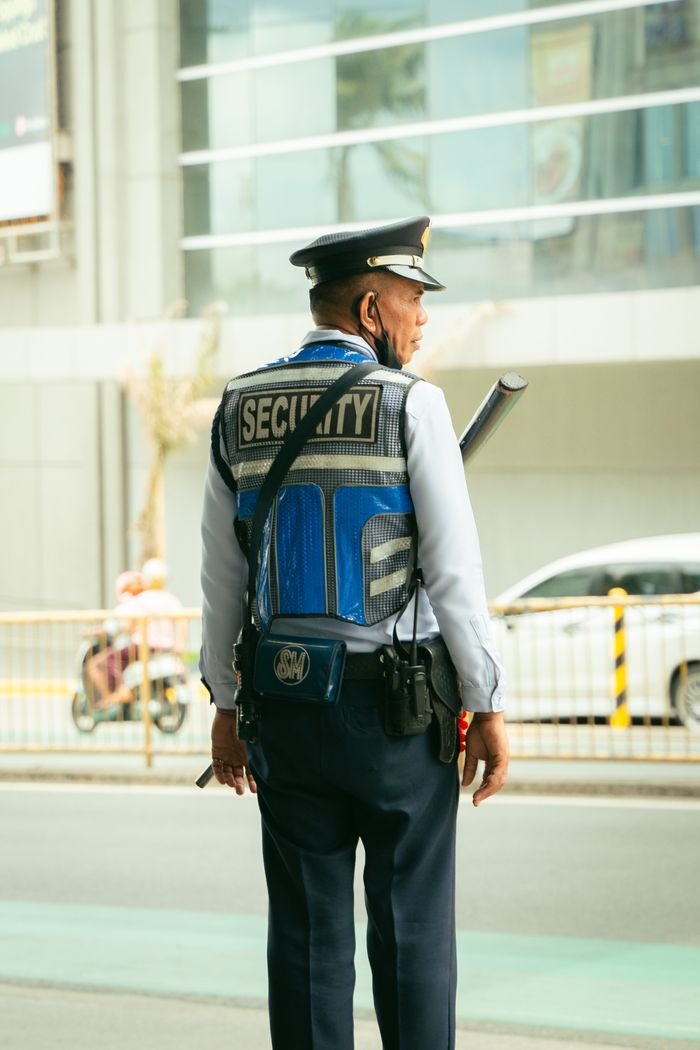 Home Security guard in uniform standing outdoors on a city street, maintaining public safety.