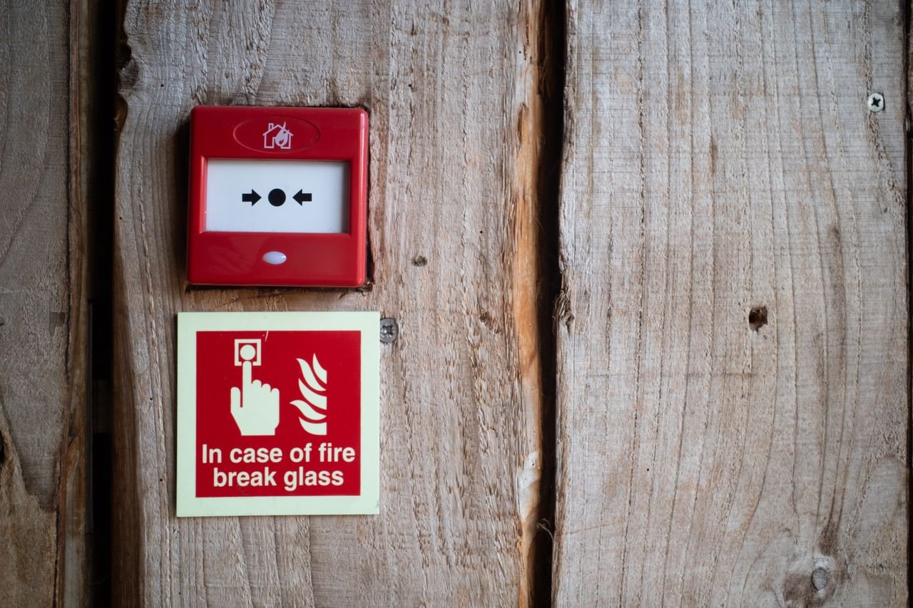 Home Red fire alarm and warning sign on a rustic wooden wall for safety awareness indoors.