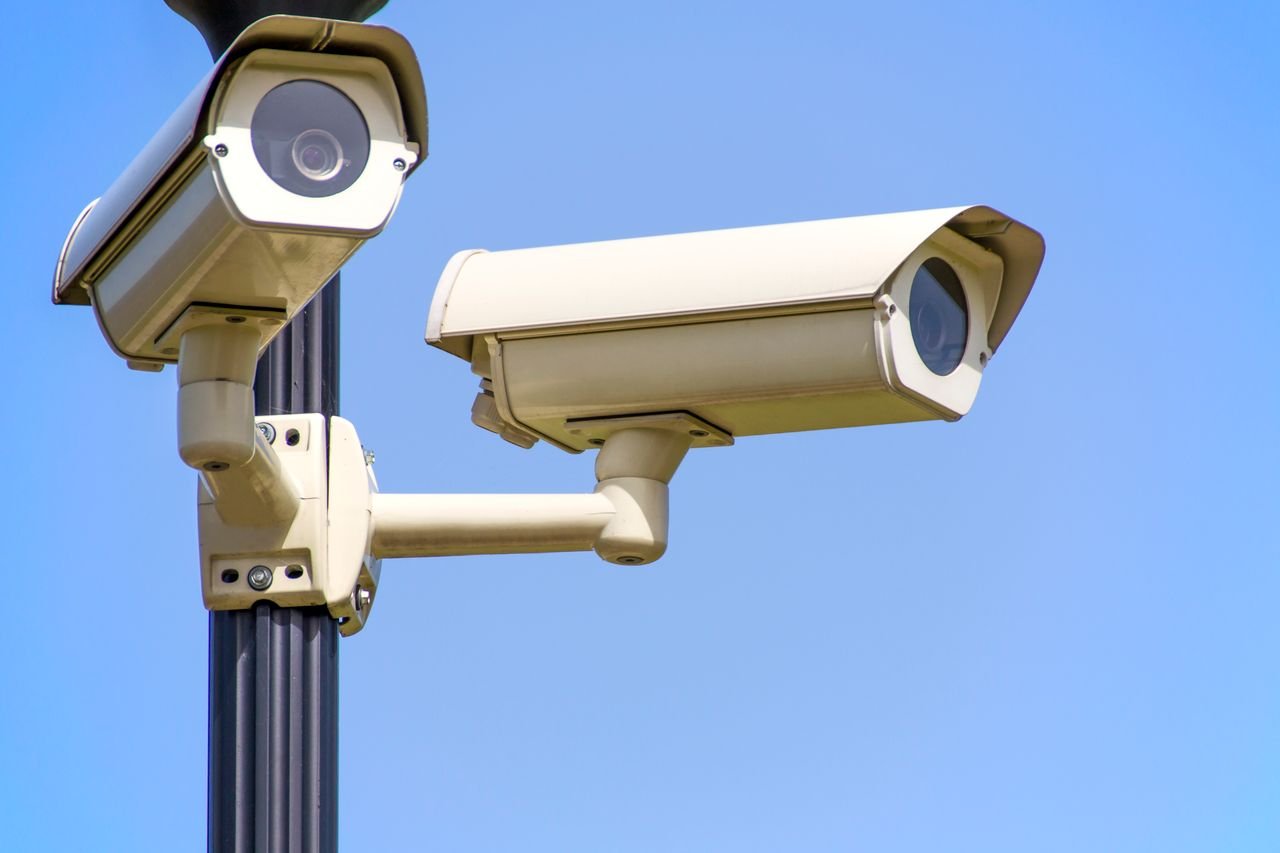 Home Outdoor security cameras mounted on a pole against a clear blue sky, ensuring vigilant surveillance.